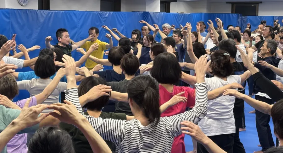 総本部で多くの塾生が円になって稽古している様子